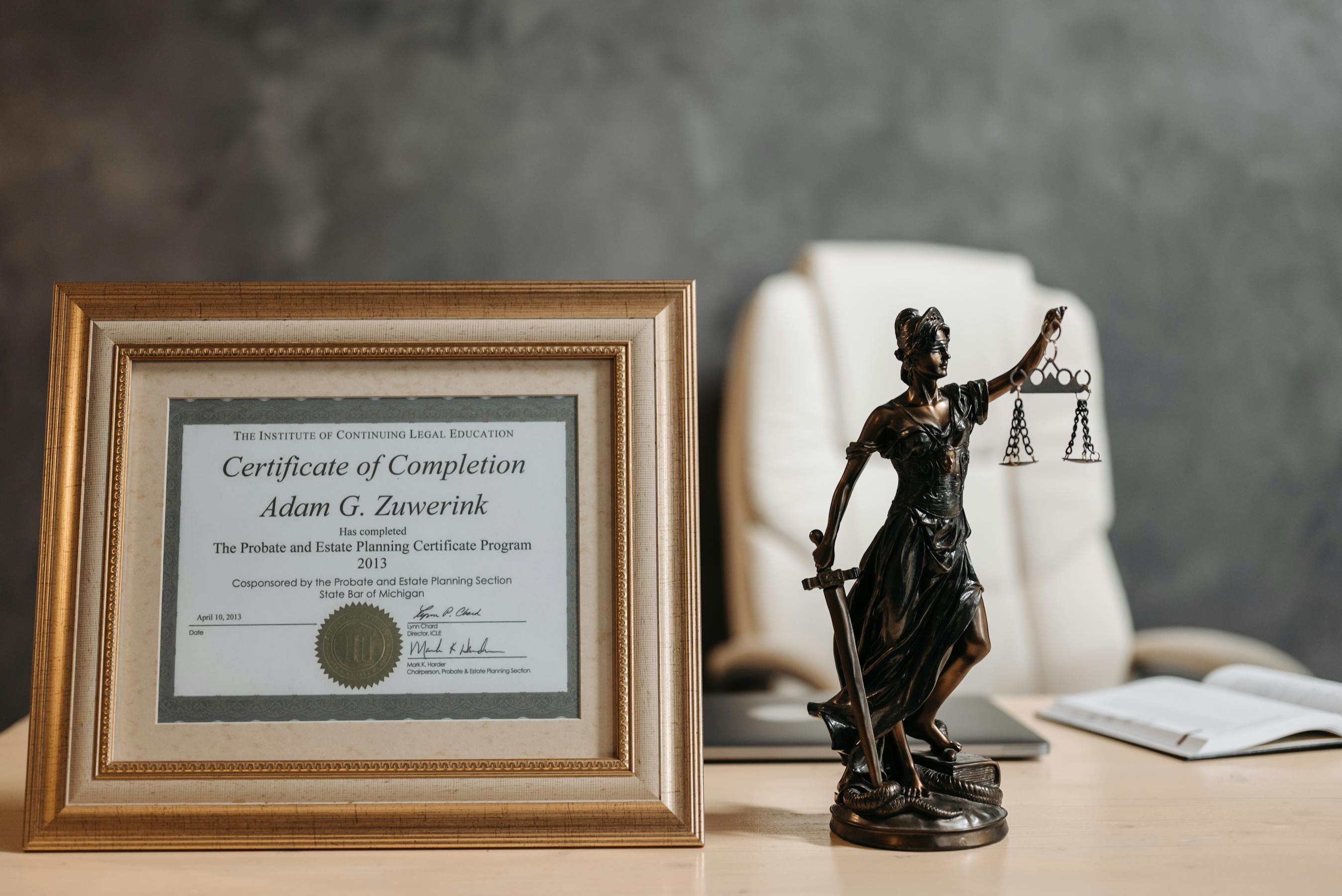 Legal certificate and Lady Justice figurine on a law-office desk
