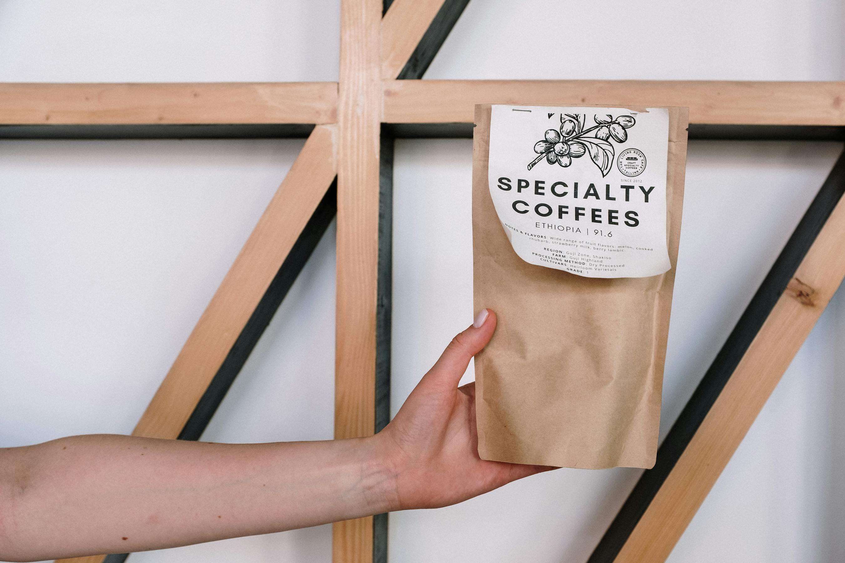 Hand holding a specialty coffee package against a minimal background